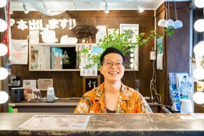 a woman sitting at a table in a restaurant at Shinagawa-shuku Guest House & Tours in Tokyo