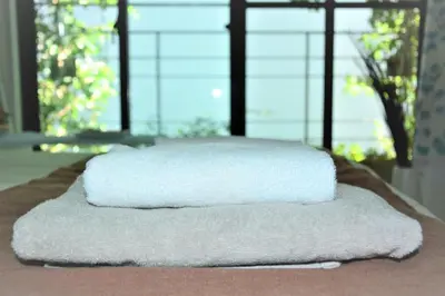 two white towels sitting on top of a bed at Shimokitazawa Independent Apartment in Tokyo