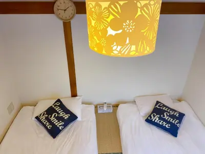 a bedroom with two beds and a clock on the wall at yikebukuro LuckyHouse \u6c60\u888b\u4e00\u8ed2\u5bb6 \u5e78\u904b\u306e\u5bb6 in Tokyo