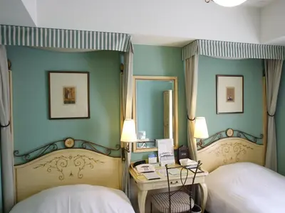 a bedroom with two beds and a desk and a mirror at Hotel Monterey Lasoeur Ginza in Tokyo