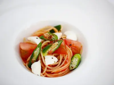 a white bowl filled with pasta and vegetables at Hotel Monterey Lasoeur Ginza in Tokyo