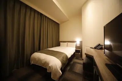 a hotel room with a bed and a flat screen tv at Dormy Inn Korakuen in Tokyo