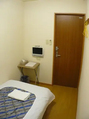 a room with a bed and a wooden door at Hotel Meigetsu in Tokyo