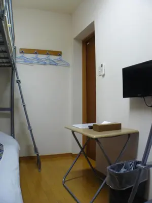 a room with a bed and a desk and a tv at Hotel Meigetsu in Tokyo