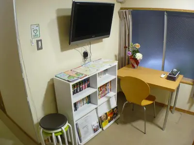 a room with a table and a desk with a tv at Hotel Meigetsu in Tokyo