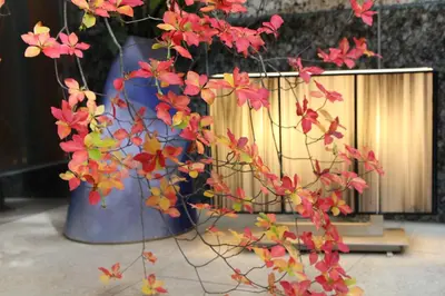 a blue vase with some red flowers in it at Hotel Apio in Tokyo