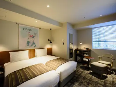 a bedroom with a bed and a desk and a window at Ebisuholic Hotel in Tokyo