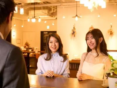 two women sitting at a table talking to a man at Ebisuholic Hotel in Tokyo