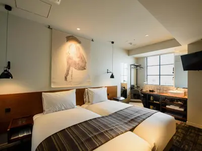 a bedroom with a bed and a bathroom with a sink at Ebisuholic Hotel in Tokyo