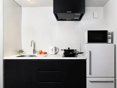 a kitchen with black cabinets and a white refrigerator at MIMARU Tokyo Ueno Inaricho in Tokyo