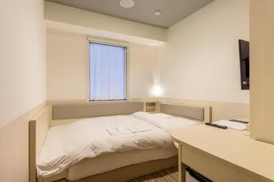a small bedroom with a bed and a window at Belken Hotel Kanda in Tokyo