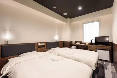 a bedroom with two beds and a flat screen tv at Belken Hotel Kanda in Tokyo