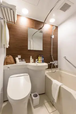 a bathroom with a toilet and a sink and a tub at Belken Hotel Kanda in Tokyo