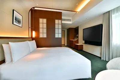 a bedroom with a large white bed and a flat screen tv at Marunouchi Hotel in Tokyo