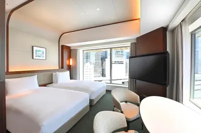 a hotel room with two beds and a tv at Marunouchi Hotel in Tokyo