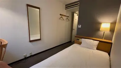 a small room with two beds and a mirror at Ueno Terminal Hotel in Tokyo