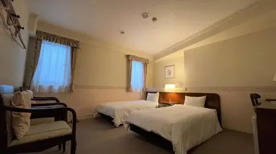 a hotel room with two beds and a chair at Ueno Terminal Hotel in Tokyo