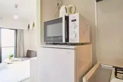 a microwave on top of a refrigerator in a kitchen at MIKO'S APT Iconic Shinjuku, lively Skyscraper view Tokyo, 10th fl, 3mins to Station 新宿 大久保のマンションで暮らす 駅チカ高層眺望 東京を楽しむ食べ歩き in Tokyo