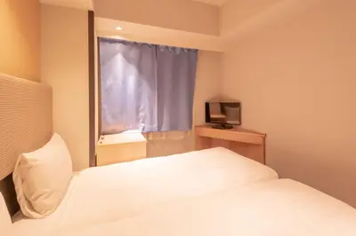 a bedroom with a white bed and a window at E Hotel Higashi Shinjuku in Tokyo