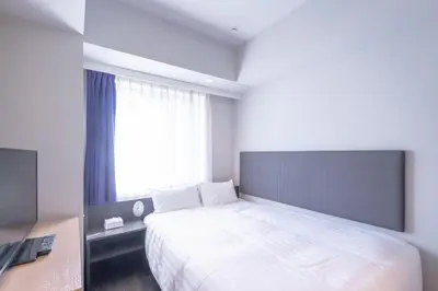 a bedroom with a large white bed and a window at E Hotel Higashi Shinjuku in Tokyo