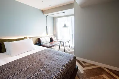 a bedroom with a bed and a chair and a table at SHIBUYA STREAM HOTEL formerly Shibuya Stream Excel Hotel Tokyu in Tokyo
