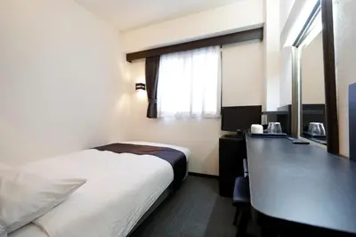 a hotel room with a bed and a desk with a computer at Tokyo Inn in Tokyo