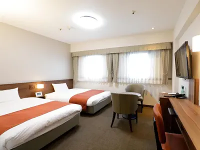 a hotel room with two beds and a flat screen tv at Tokyo Inn in Tokyo