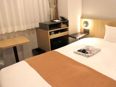 a hotel room with a bed with a towel on it at Tokyo Inn in Tokyo