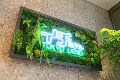 a sign on the side of a building with plants at ICI HOTEL Ueno Shin Okachimachi in Tokyo