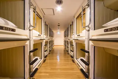 a long hallway with many empty shelves in a room at Shinjuku Kuyakusho-mae Capsule Hotel in Tokyo