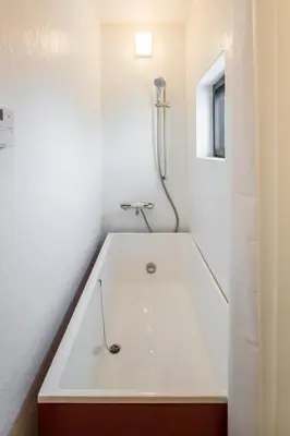 a white bath tub in a bathroom with a window at Smi:re Stay Oshiage in Tokyo