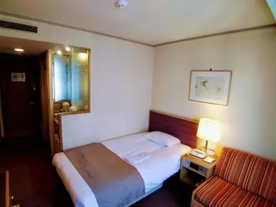 a hotel room with a bed and a chair at Tokyo Grand Hotel in Tokyo