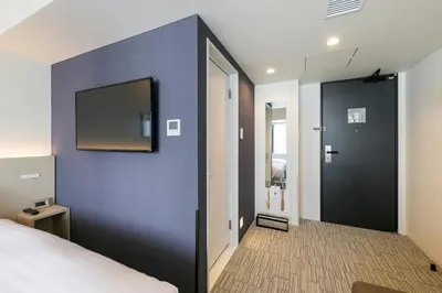a bedroom with a blue wall with a tv on it at Ginza Capital Hotel Moegi in Tokyo