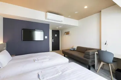 a hotel room with two beds and a couch at Ginza Capital Hotel Moegi in Tokyo