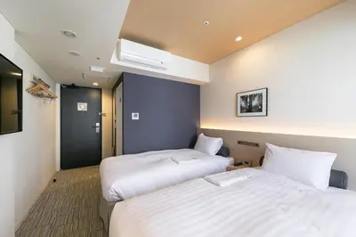 a hotel room with two beds and a window at Ginza Capital Hotel Moegi in Tokyo