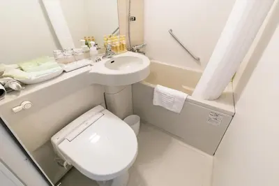a white bathroom with a toilet and a sink at Ginza Capital Hotel Moegi in Tokyo