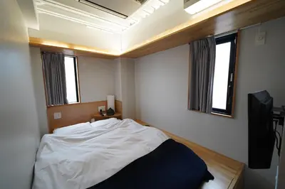 a bedroom with a white bed and a television at plat hostel keikyu asakusa station in Tokyo