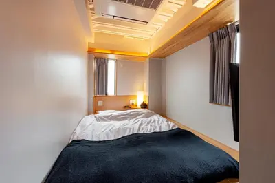 a small bedroom with a bed and a window at plat hostel keikyu asakusa station in Tokyo
