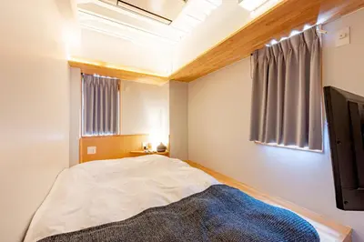 a small bedroom with a bed and a window at plat hostel keikyu asakusa station in Tokyo