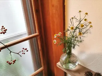 a vase with flowers on a shelf next to a window at Komatsuya in Tokyo