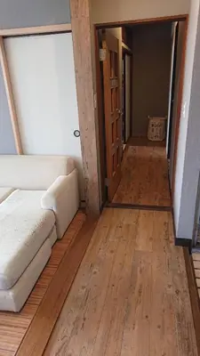 a living room with a couch and a wooden floor at GUEST HOUSE SaKURa in Tokyo
