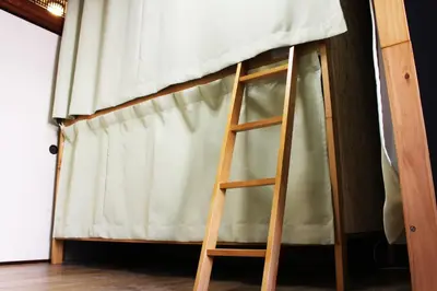 a ladder leaning against a bed with a curtain at GUEST HOUSE SaKURa in Tokyo