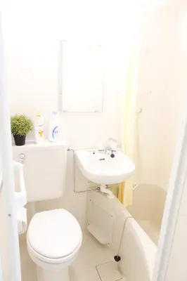 a white bathroom with a toilet and a sink at Shinjuku Sky hostel in Tokyo