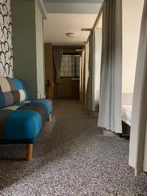 a hotel room with a bed and a blue couch at Shinjuku Sky hostel in Tokyo