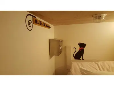 a black cat sitting on the corner of a room at Shinjuku Sky hostel in Tokyo