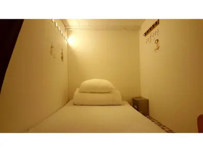 a small room with a bed with a white blanket at Shinjuku Sky hostel in Tokyo