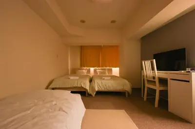 a hotel room with two beds and a desk and a television at HIROKI Building in Tokyo