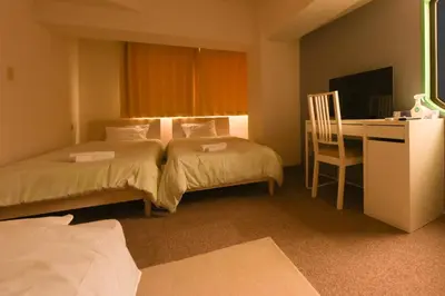 a hotel room with two beds and a desk with a computer at HIROKI Building in Tokyo