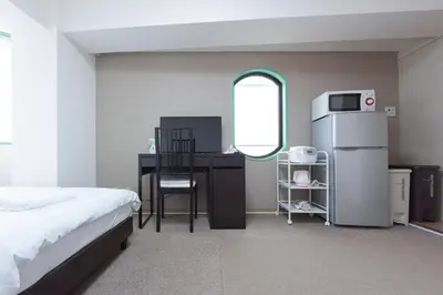 a bedroom with a desk and a refrigerator and a table at HIROKI Building in Tokyo