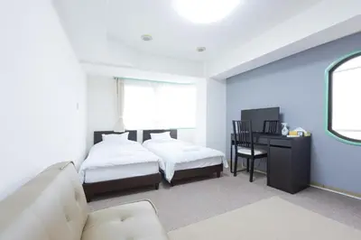 a bedroom with two beds and a desk and a couch at HIROKI Building in Tokyo